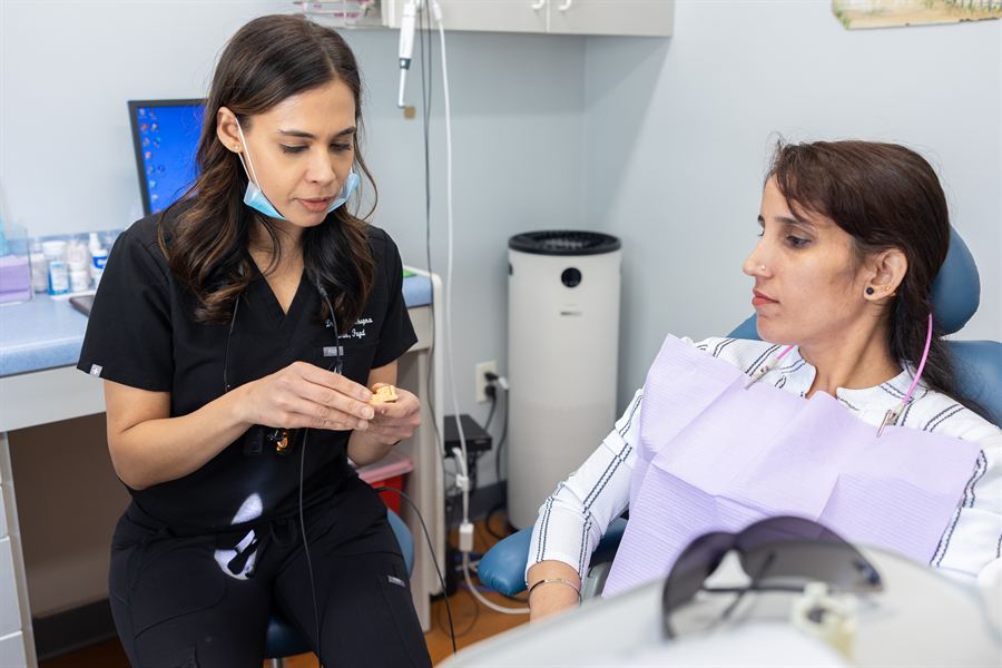 Kirti Chopra, DDS, FAGD explaining treatment with a dental model at Smile Design Studio by KC